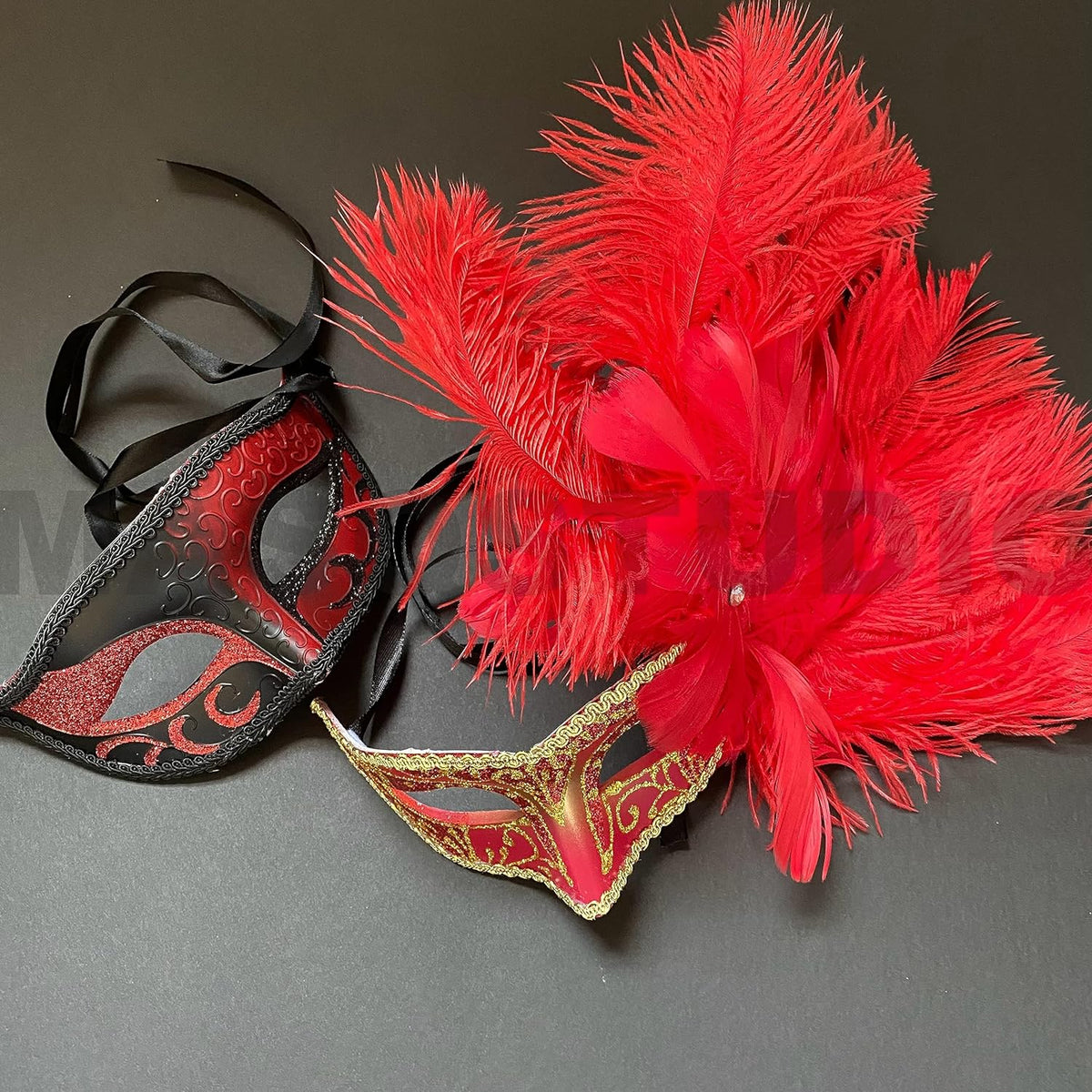 Red and black Mardi Gras masquerade mask pair with red feathers on dark background