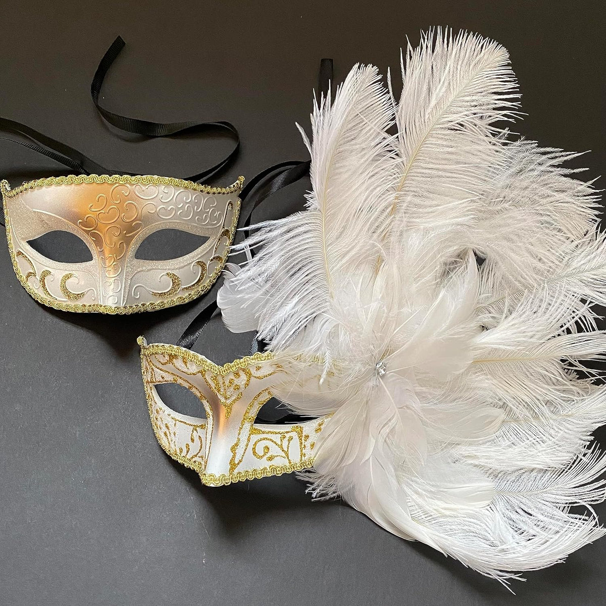 White and gold Mardi Gras masquerade mask pair with white feathers on dark background